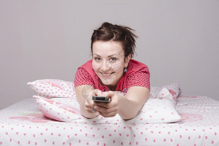 一个年轻女孩在床上看电视图片