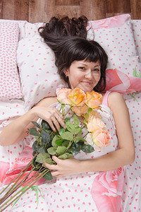一个睡在床上送花的年轻美女图片