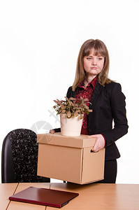 办公室解雇的妇女在办公室工作时悲伤地看着一个盒子和手拿着一朵花的盒子和盆图片