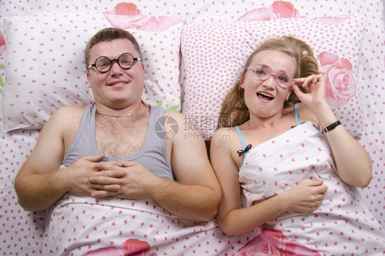 睡在床上的年轻夫妇穿着每件圆滑的眼镜图片