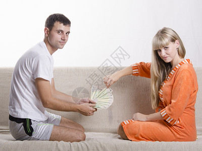 夫妻坐在沙发上互相对质丈夫认为工资是收到的妻子抽一张钞票图片