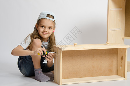 小女孩家具收藏在胸前木框中用螺丝刀扭起子图片