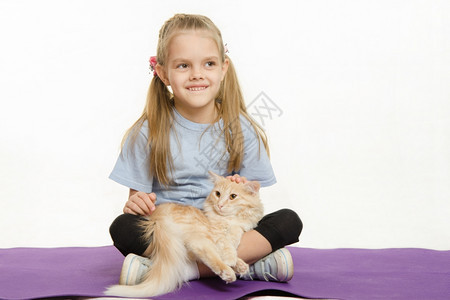 和猫一起坐在地毯上的快乐女孩6岁的欧洲女孩在与家猫一起坐地毯上运动后在与家猫一起坐地毯上运动之后在6岁的欧洲女孩坐在地毯上图片