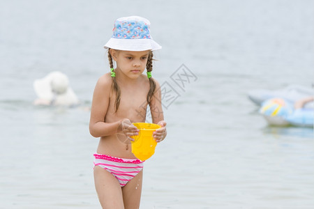 5岁女孩在海滩上用桶装水有趣的5岁女孩在海滩上玩沙模图片