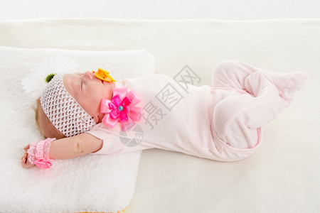 一个两月的欧洲女婴背着绷带头部有柔软床上躺着一朵花图片