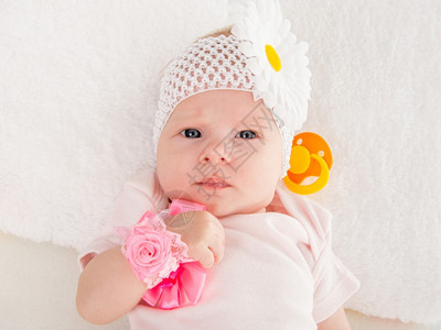 一个两月的欧洲女婴背上戴绷带头部躺着一朵花在张软床上图片