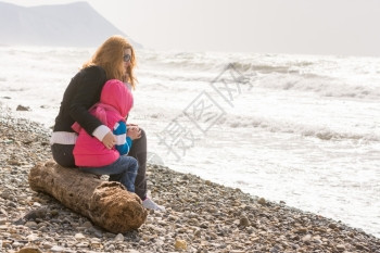 我妈和五岁的女儿坐在沙滩上我妈抱着她冷冻的女孩图片