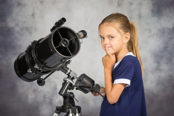 7岁女孩深思熟虑地看着照片站在望远镜上图片