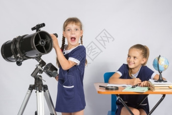 女孩惊讶的天文学家通过望远镜观察另一女孩看着她图片
