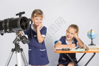 一个女孩在操作望远镜另一个女孩嘲笑她图片