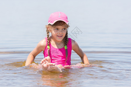 身着帽子的女孩坐在水中浅河边图片