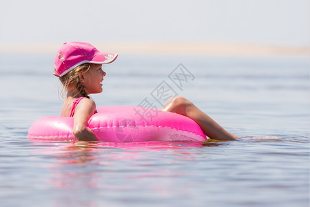 在河里游泳的帽子女孩坐在游泳圈上图片