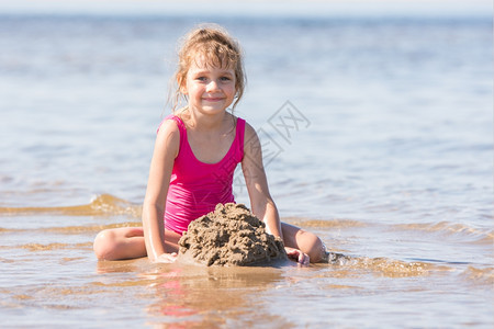 穿粉红色泳衣的5岁女孩在河边浅海的沙滩上玩图片