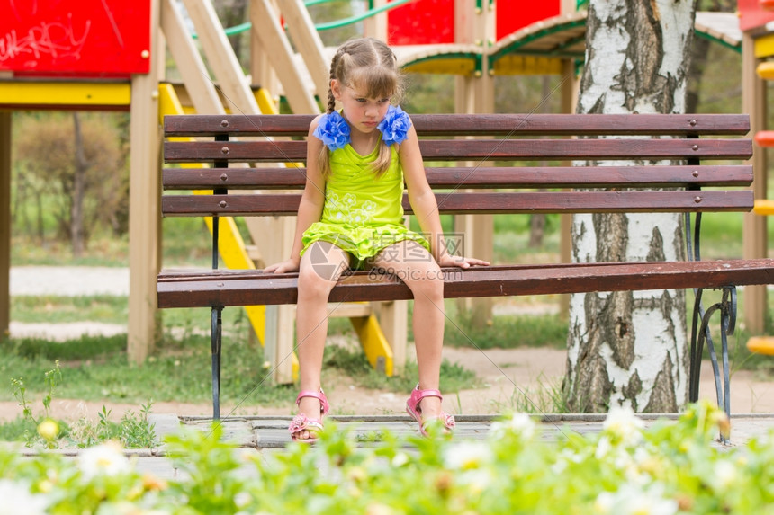 女孩坐在公园椅子上不开心图片