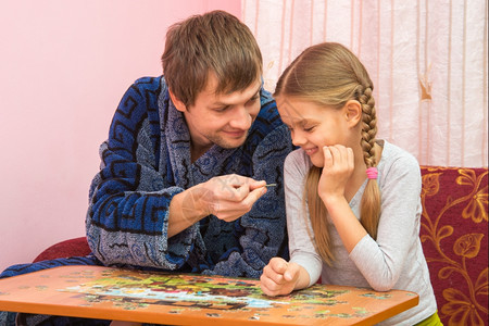爸爸和女儿在桌子上玩拼图图片