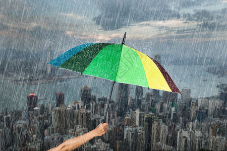 香港市背景雨下手持多彩伞图片