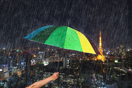 日本东京市背景下着雨手持多彩伞图片