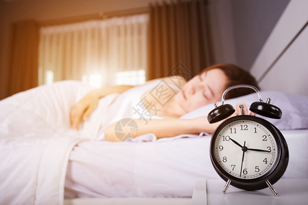 时钟显示上午10点女人早上睡在床阳光照耀图片