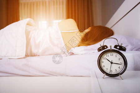 时钟显示上午10点女人早上睡在床阳光照耀图片