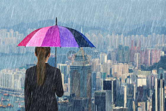 拥有多色雨伞在城市背景下降雨的女商人图片