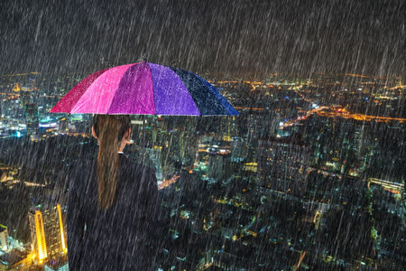 泰国曼谷市背景雨下拥有多彩伞的女商人图片