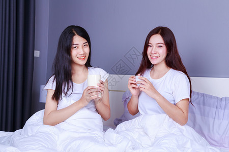 两个最好的朋友聊天和在卧室的床上喝杯咖啡图片