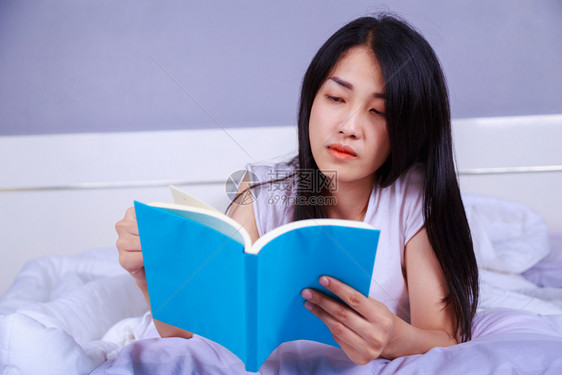 女人在家里卧室的床上看书图片