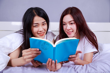 两个女人在卧室的床上看书图片