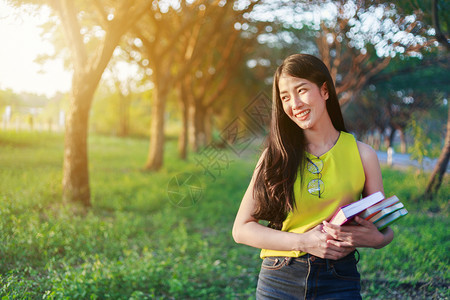 在公园里拿着一本书的年轻女子图片