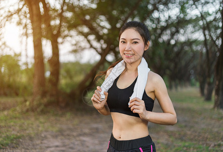 在公园户外运动后带白毛巾的年轻运动女青者休息图片