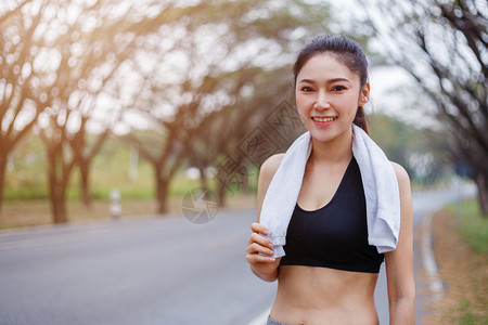 在公园户外运动后带白毛巾的年轻运动女青者休息图片