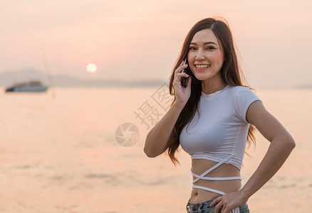 女在海滨日落时使用手机美丽的女在海滨日落时使用手机图片