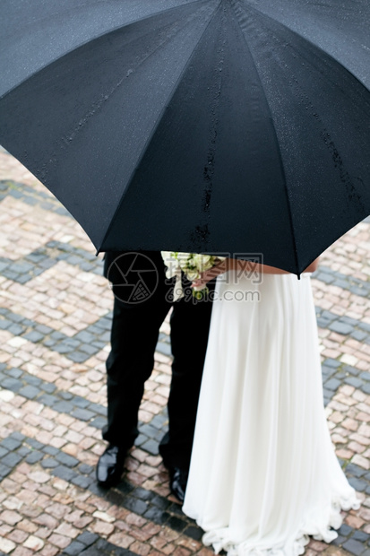 新娘和郎在雨伞下盛着一束鲜花图片