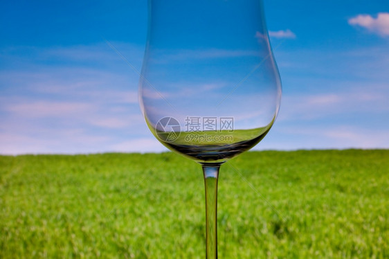 概念上点亮的葡萄酒玻璃天空和绿草的底图片