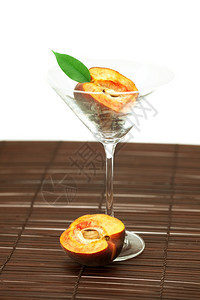 玛蒂尼酒杯中的桃子在竹垫上图片