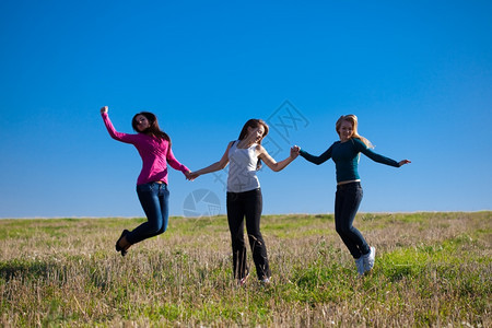 三名姑娘田野中跳跃图片