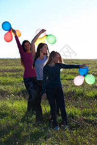三个美丽的年轻姑娘带着气球飞入田地与天空对着图片