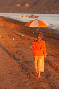 小女孩在阳光照耀的海滩上奔跑图片