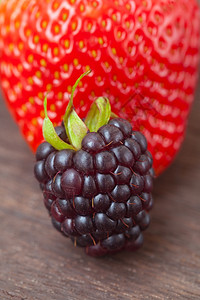 木表面的红多汁草莓和黑图片