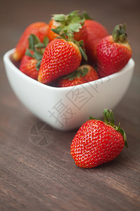 在木质表面的碗里吃红色多汁草莓图片