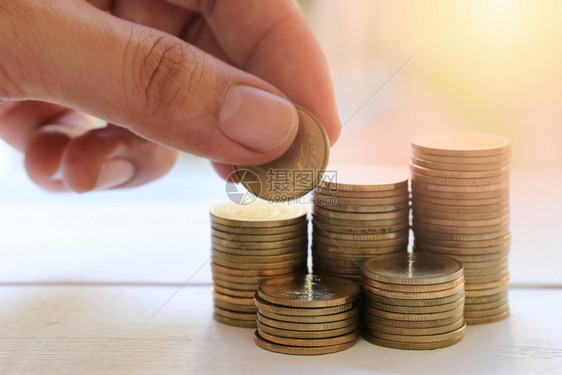 商业图中的硬币堆在白桌上手握着商业图中的硬币堆在白桌上手放一块硬币上用来设计想法供您在作品中展示图片