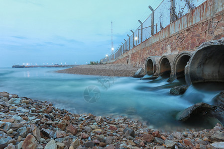 水流入海中的排水管晚上有水流入海中的排水管背景图片