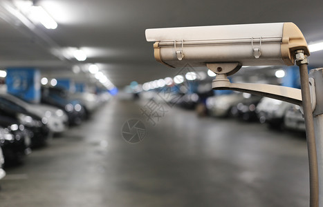 闭路电视摄像头显示汽车停放和照明灯模糊闭路电视摄像头显示汽车停放和灯模糊亮亮的停车地点概念安全和技术图片