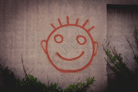 混凝土墙上红色快乐笑脸的涂鸦图片