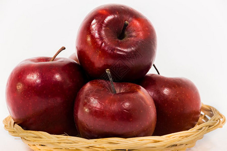在白色背景中隔绝的维杰篮子里紧贴着成熟的红苹果图片