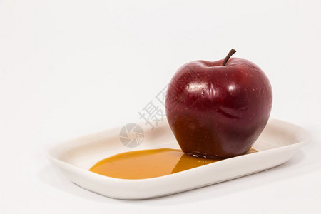 红色苹果在白盘子上蜂蜜在白色背景上被孤立图片
