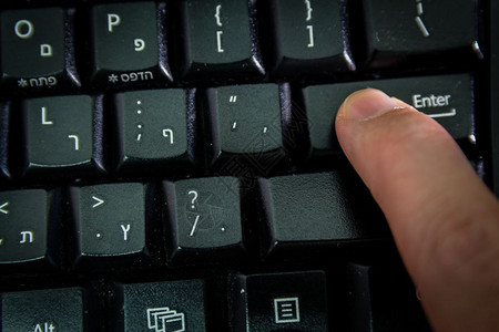 男人在无线键盘上打字用希伯来语和英字母打按Enter键顶视图黑暗气氛图片