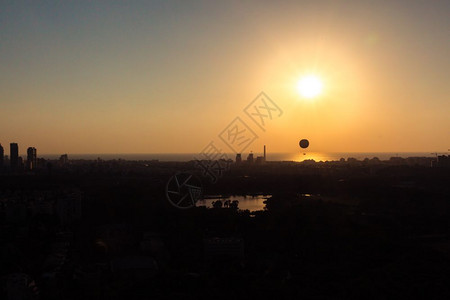 日落时特拉维夫天际线日落时光环可以看到一个热气球在空中飞翔此外还可以看到北特拉维夫哈亚肯公园阅读电站和地中海的附近区图片
