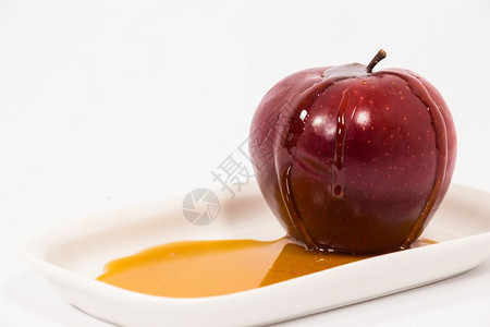 红色苹果白盘子上有一滴蜂蜜在白色背景上孤立着蜂蜜犹太新年的符号RoshHashanah图片