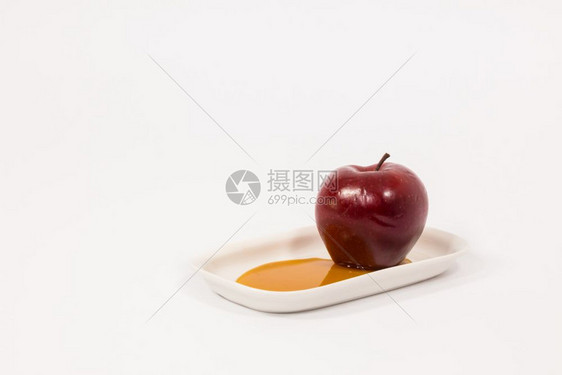 红色苹果在白盘子上蜂蜜在白色背景上被孤立图片